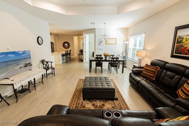 living room with light hardwood / wood-style floors and a raised ceiling