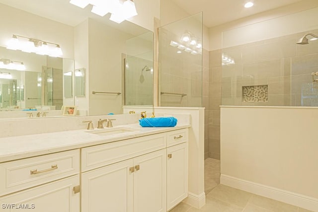 bathroom with tile patterned floors, a tile shower, and vanity