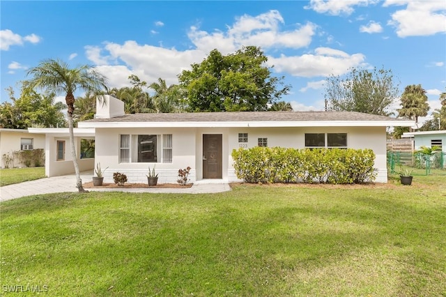 ranch-style home featuring a front lawn, a chimney, and stucco siding