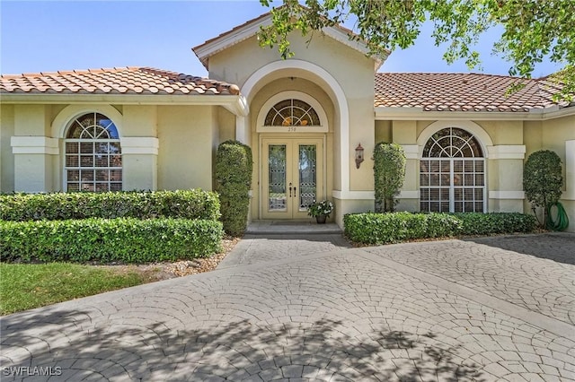 property entrance featuring french doors, a tiled roof, and stucco siding