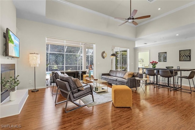 living room featuring ornamental molding, wood finished floors, a ceiling fan, and baseboards