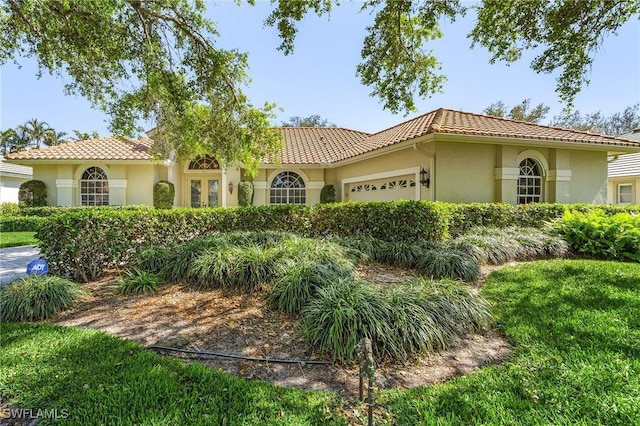 mediterranean / spanish-style house with a tiled roof, an attached garage, and stucco siding