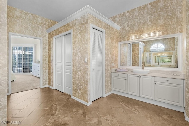 bathroom with wallpapered walls, baseboards, vanity, a healthy amount of sunlight, and a closet