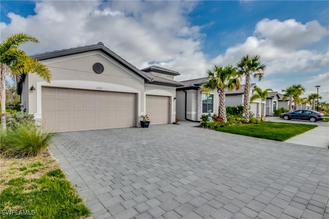 view of front of property featuring decorative driveway, an attached garage, and stucco siding