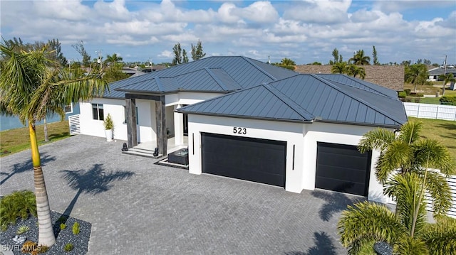 view of front of property with a garage, metal roof, a standing seam roof, decorative driveway, and stucco siding