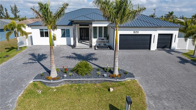 view of front of house with a garage, metal roof, a standing seam roof, and stucco siding