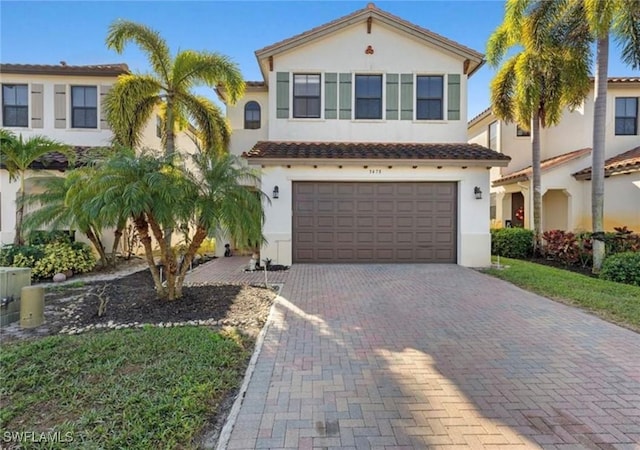 view of front of house featuring decorative driveway, a tiled roof, stucco siding, and a garage