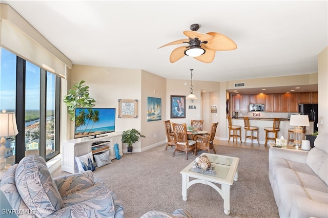 living area featuring light colored carpet, visible vents, ceiling fan, and baseboards