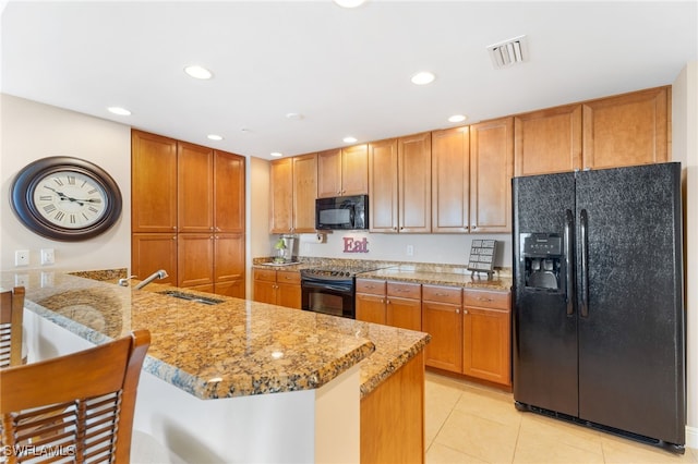 kitchen with a sink, a peninsula, a kitchen breakfast bar, black appliances, and visible vents