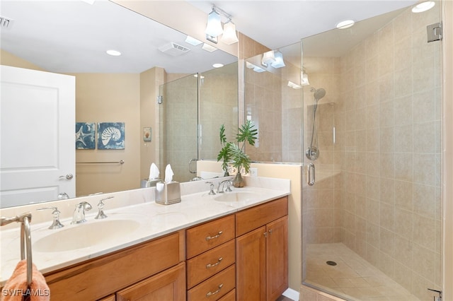 bathroom with double vanity, a stall shower, a sink, and visible vents