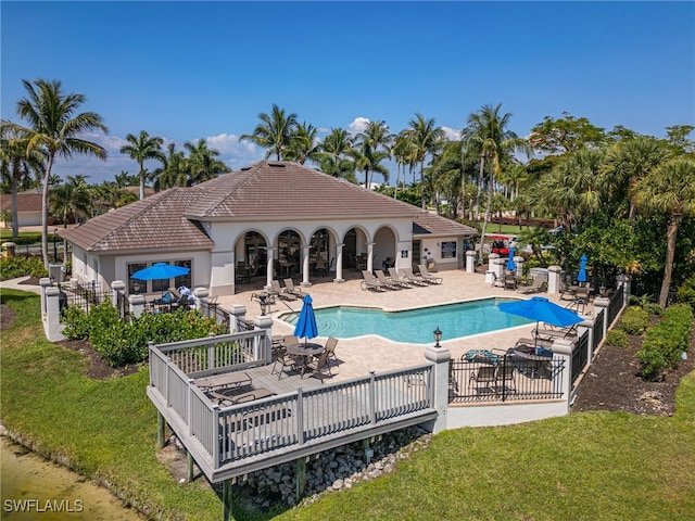 back of property with a yard, a tiled roof, a patio area, and a community pool