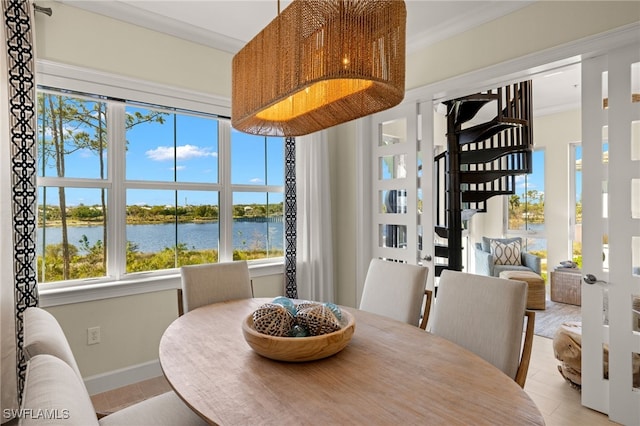 dining room featuring a water view, light tile patterned floors, baseboards, and ornamental molding