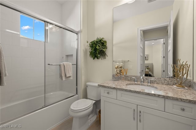 full bath with combined bath / shower with glass door, vanity, and toilet