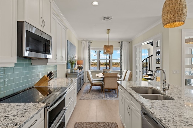 kitchen featuring stainless steel appliances, visible vents, a sink, and crown molding