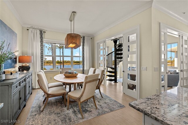 dining space featuring a water view, crown molding, and stairs