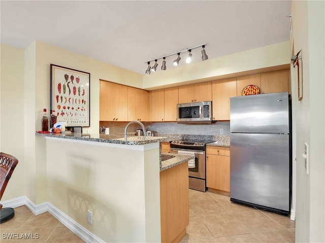 kitchen featuring appliances with stainless steel finishes, tasteful backsplash, stone counters, light tile patterned flooring, and kitchen peninsula