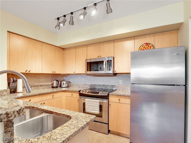 kitchen featuring appliances with stainless steel finishes, sink, backsplash, and light brown cabinetry