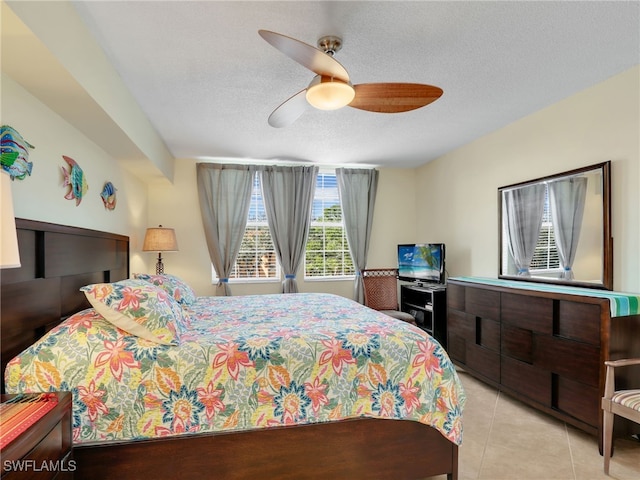 tiled bedroom with ceiling fan and a textured ceiling