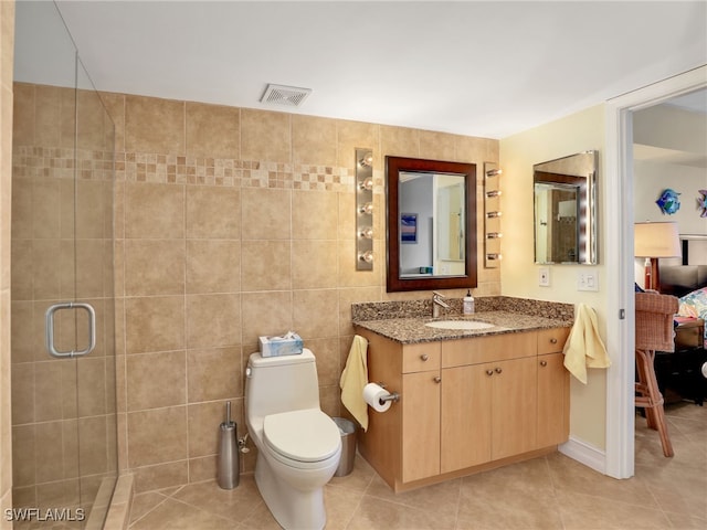 bathroom with an enclosed shower, tile patterned flooring, toilet, tile walls, and vanity