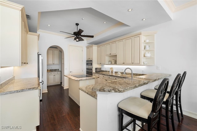 kitchen with cream cabinets, a peninsula, dark wood finished floors, open shelves, and a ceiling fan
