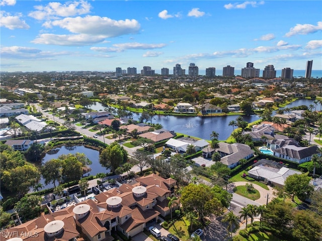 aerial view of property and surrounding area with a large body of water, a view of skyline, and nearby suburban area