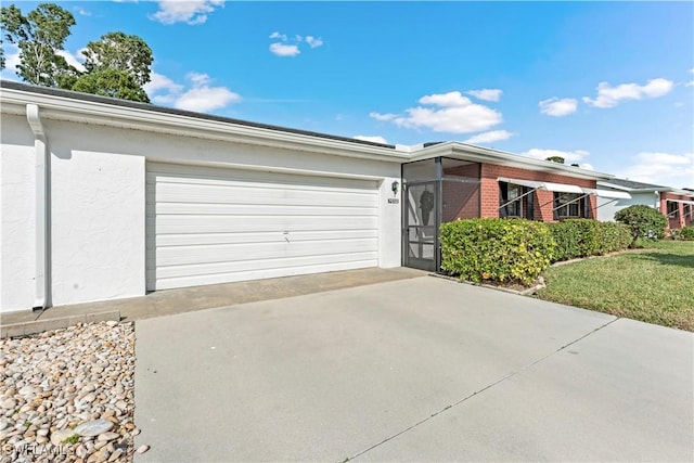 single story home featuring concrete driveway, brick siding, a garage, and stucco siding