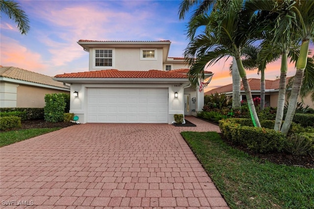 mediterranean / spanish-style home with stucco siding, a tile roof, and decorative driveway