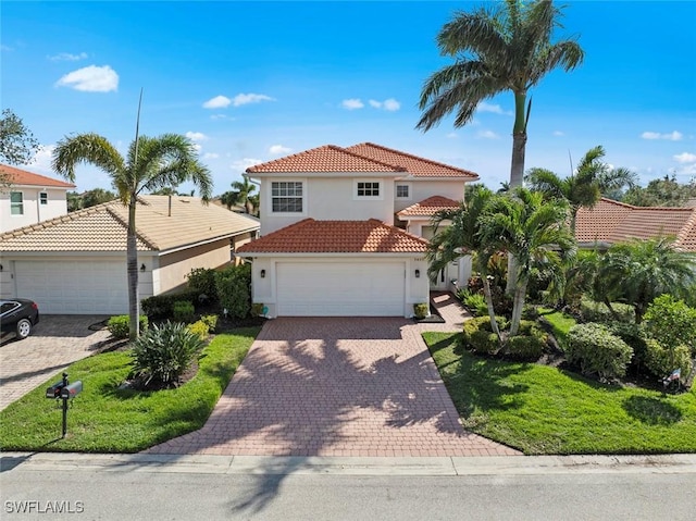 mediterranean / spanish home with a tile roof, decorative driveway, and stucco siding