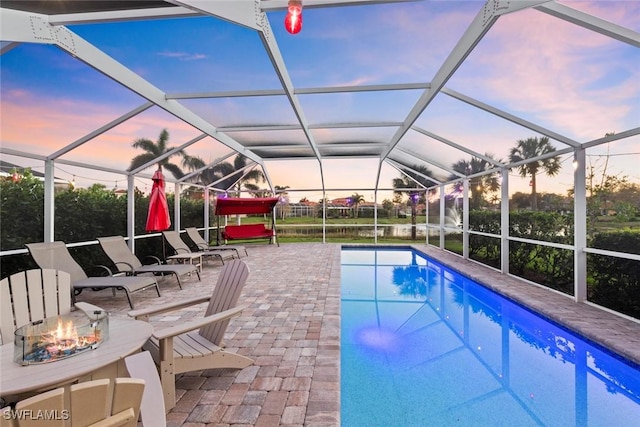 outdoor pool with a patio, a fire pit, and glass enclosure