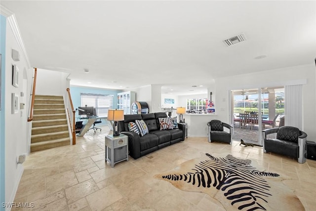 living area featuring a healthy amount of sunlight, stone tile floors, stairway, and visible vents