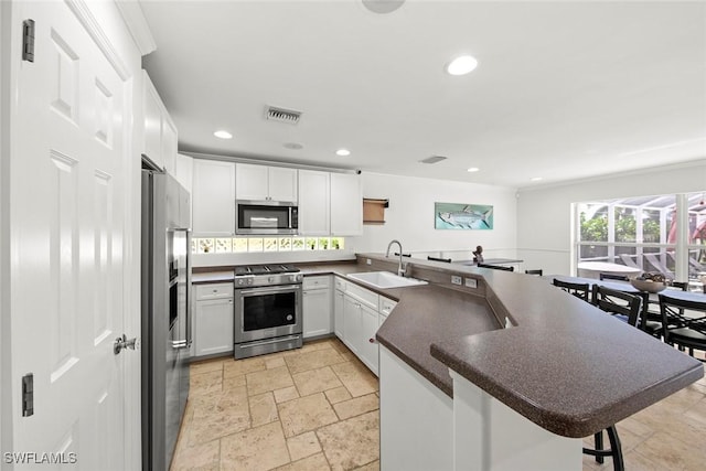 kitchen featuring a sink, a peninsula, dark countertops, stainless steel appliances, and visible vents