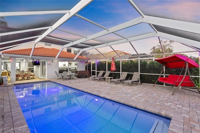 outdoor pool with glass enclosure and a patio