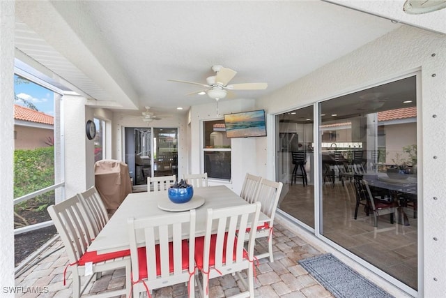 sunroom / solarium with outdoor dining area and a ceiling fan