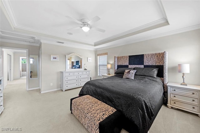 bedroom with a tray ceiling, a ceiling fan, ornamental molding, and light carpet