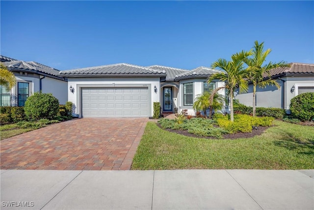 view of front of home with a garage, a tile roof, decorative driveway, stucco siding, and a front lawn