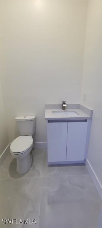 bathroom with toilet, baseboards, and vanity