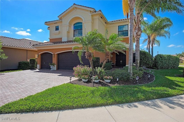 mediterranean / spanish-style home featuring a tiled roof, a front lawn, decorative driveway, and stucco siding