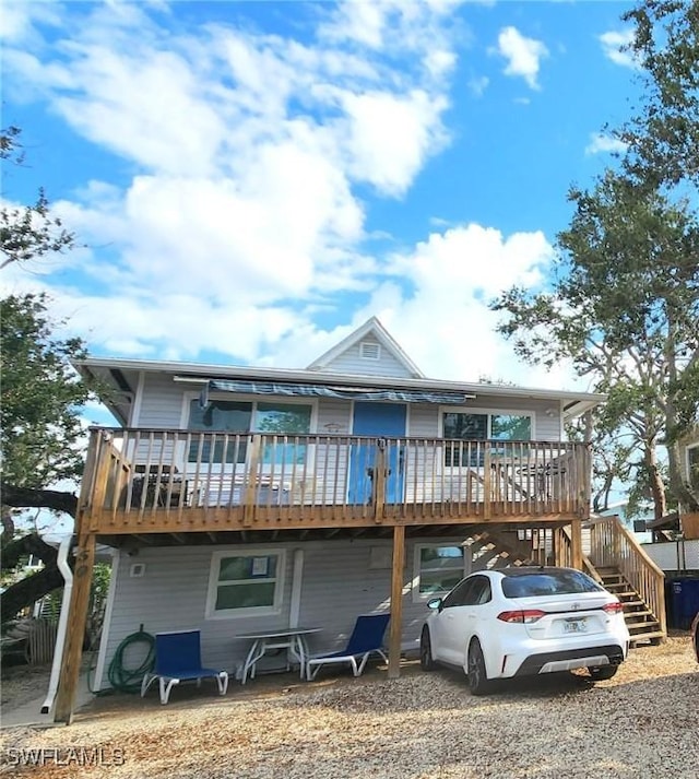 view of front of home with driveway, stairway, a carport, and a wooden deck