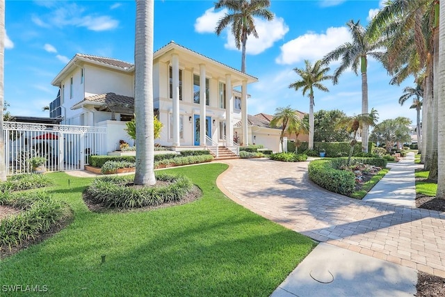 view of front of property with a front lawn, a tile roof, fence, and stucco siding