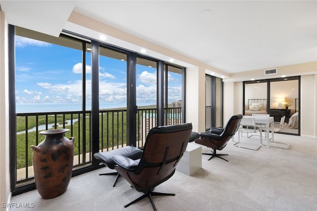 living area with a water view, visible vents, and light colored carpet