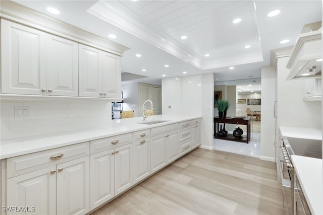 kitchen with recessed lighting, white cabinets, light countertops, light wood-type flooring, and a raised ceiling