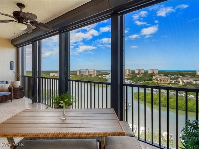 unfurnished sunroom with plenty of natural light, ceiling fan, and a water view