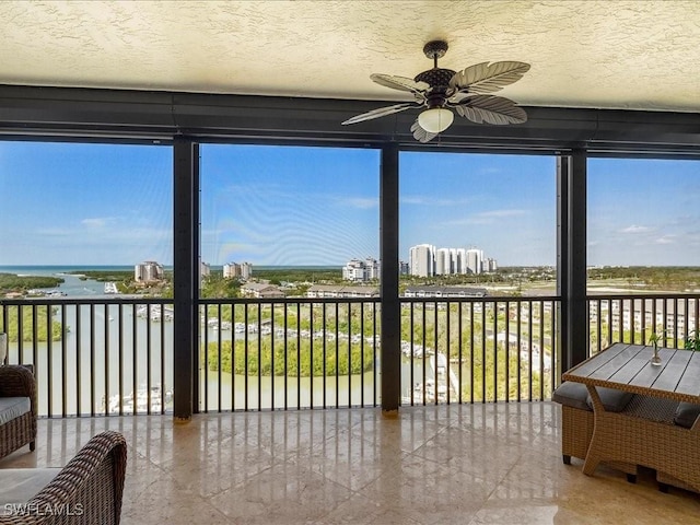 sunroom / solarium with a water view, plenty of natural light, and a ceiling fan