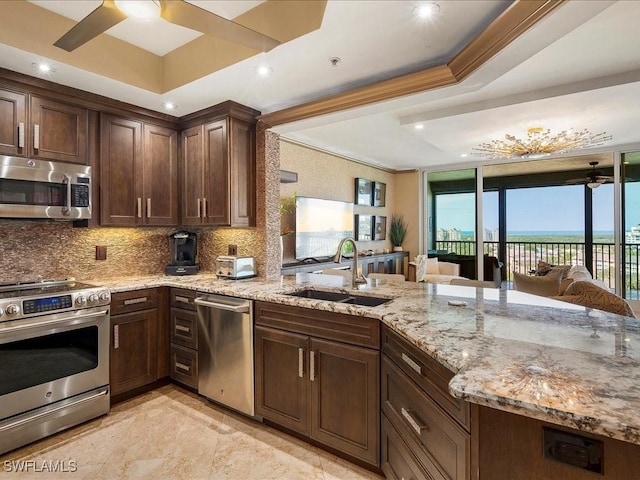 kitchen with open floor plan, stainless steel appliances, a sink, and a raised ceiling