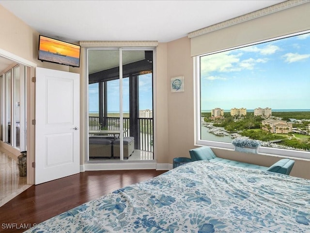 bedroom featuring access to exterior, a view of city, dark wood-type flooring, and baseboards