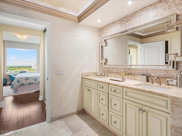 ensuite bathroom with double vanity, a sink, connected bathroom, and crown molding