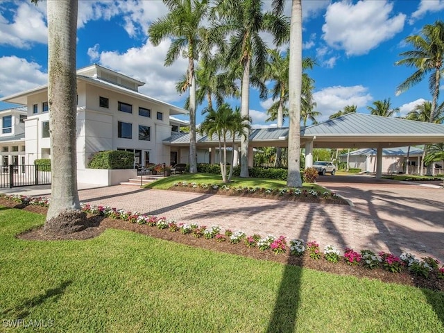 view of property's community with an attached carport, a yard, and driveway