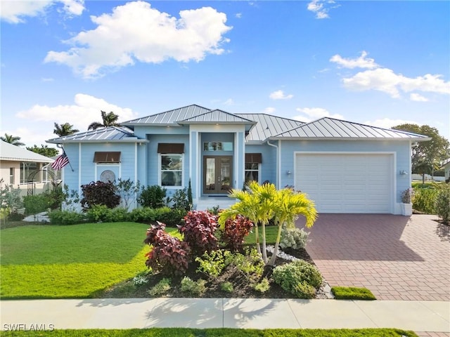 view of front of home with decorative driveway, a standing seam roof, an attached garage, and a front yard