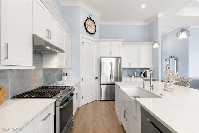 kitchen featuring under cabinet range hood, a sink, white cabinetry, hanging light fixtures, and appliances with stainless steel finishes