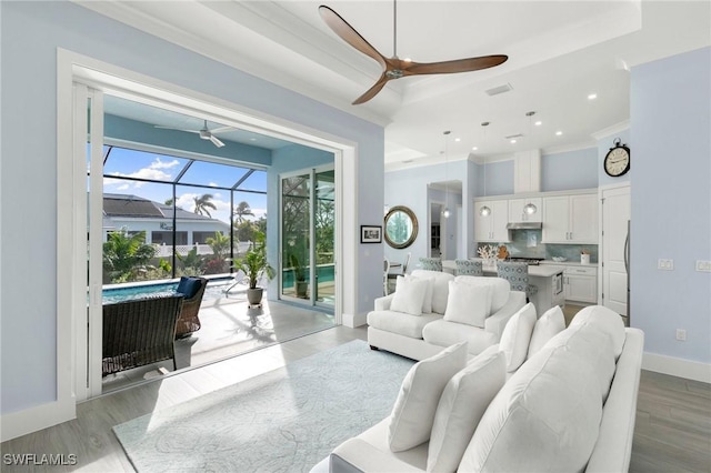 living area with a ceiling fan, light wood-type flooring, a sunroom, and baseboards